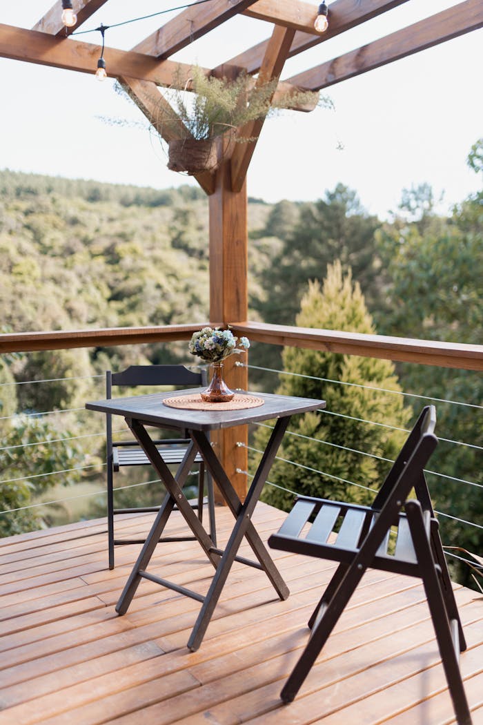 A charming outdoor dining setup on a wooden deck overlooking lush forest scenery.
